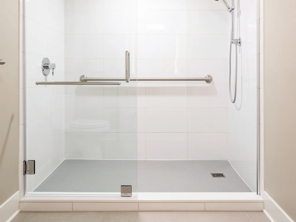 Douche de plain-pied posée à la place d'une baignoire, accès sans marche et barre d'appui