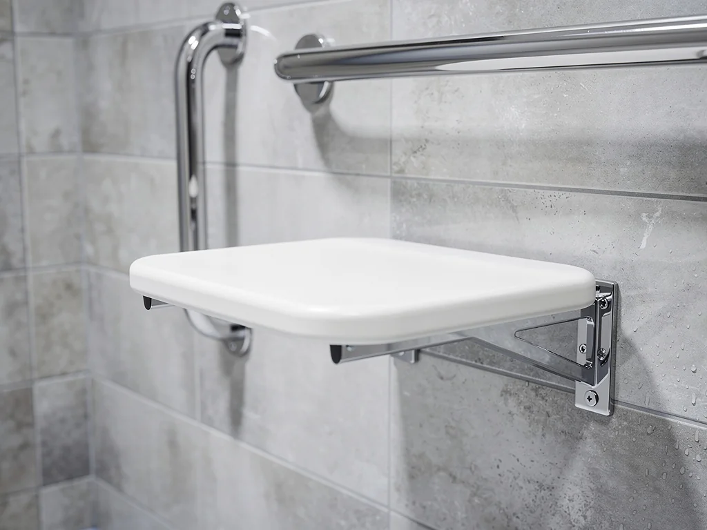 Siège de douche rabattable et barres de maintien chromées dans une cabine adaptée